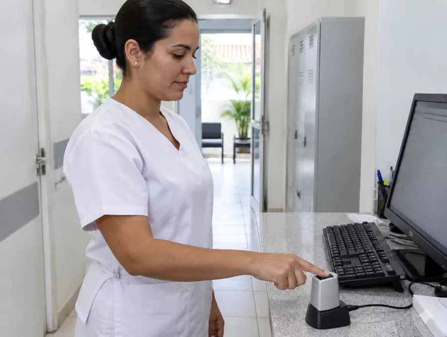 Enfermeira encostando o dedo no leitor na entrada da clínica